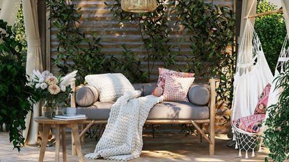 Herringbone patterned tiled patio floor with a grey sofa with a chunky throw and cushions