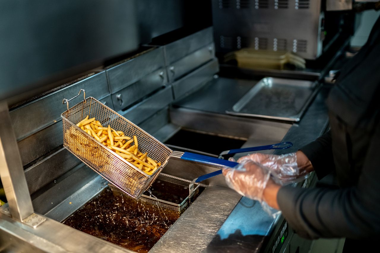 A person flips fries in a fryer.