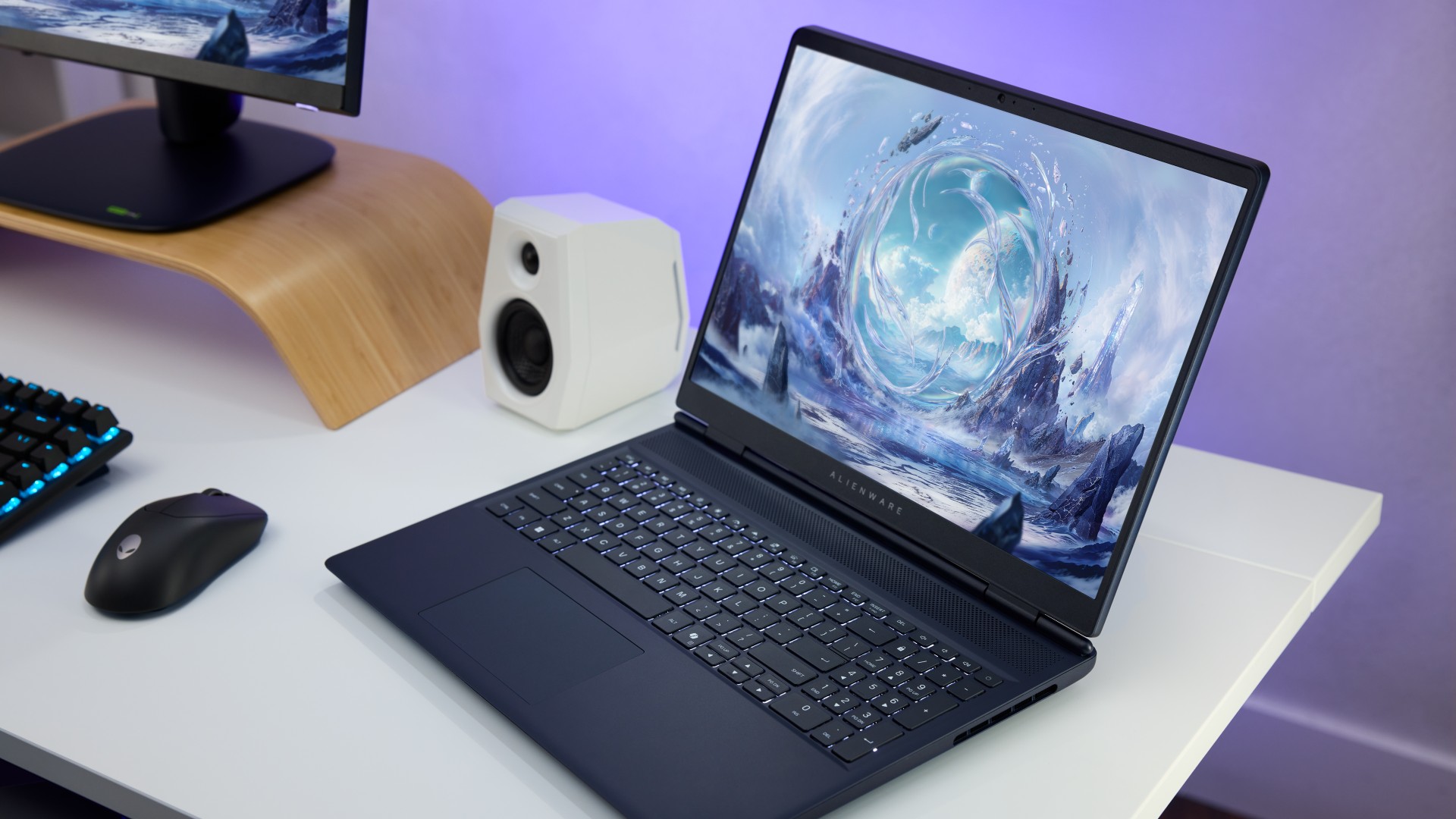 Alienware Aurora 16 gaming laptop on a white desk setup with a speaker and monitor in the corner