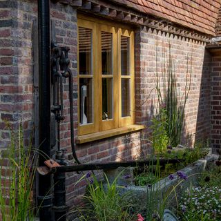 wooden window frame set in brick with planter and garden under window