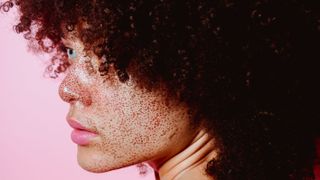 profile of young womans back with natural hair and freckles