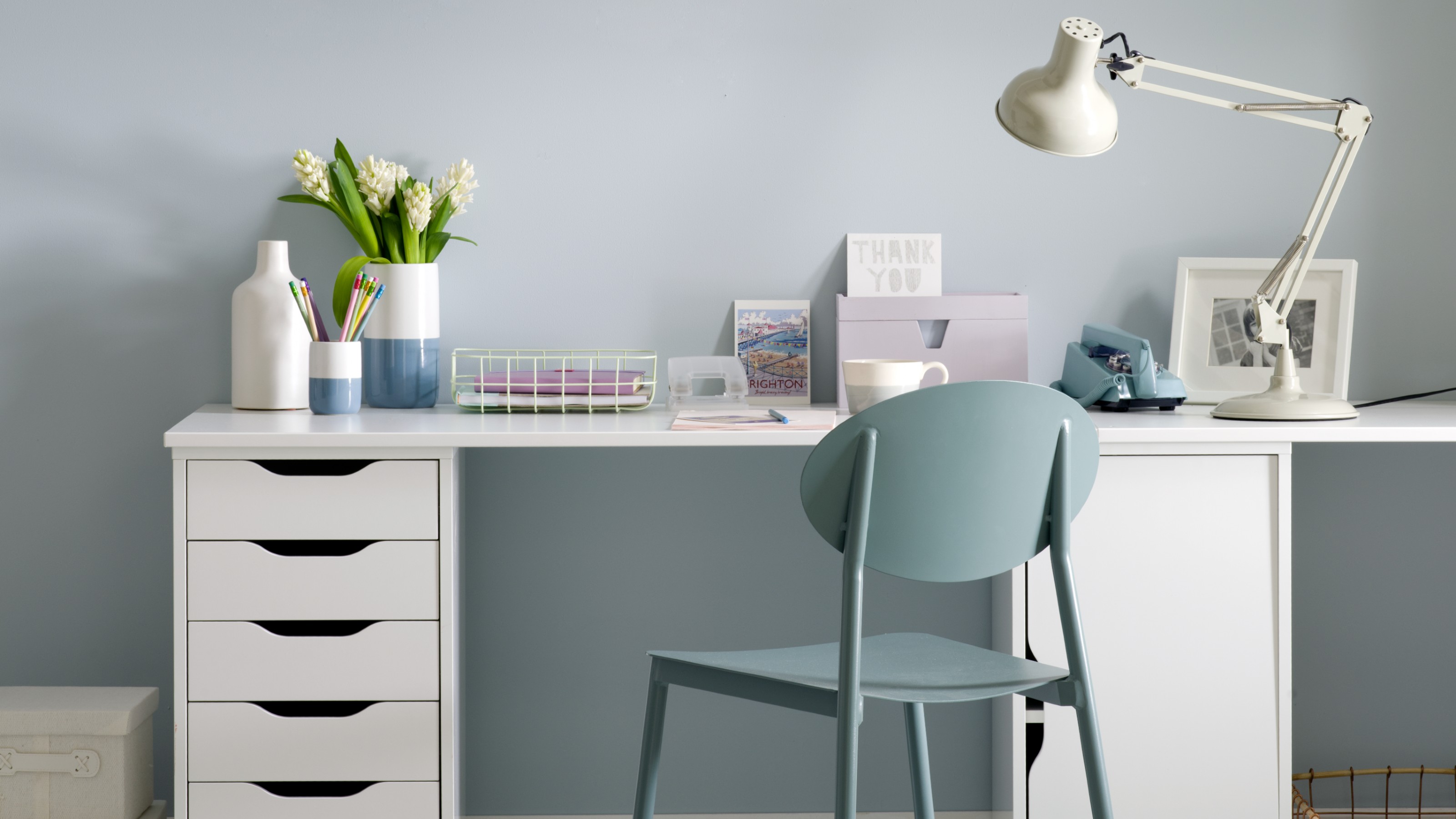A blue home office with a white IKEA desk with drawers and a blue chair