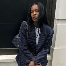 @nlmarilyn wearing a navy blue pinstripe suit with a navy blue Chanel quilted flap bag.