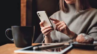 A woman holding an iPhone near an iPad