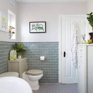 bathroom with grey wall tiles and white door with commode