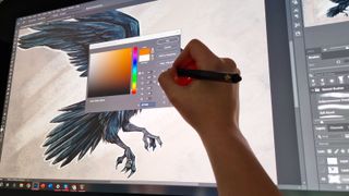 A photo of a hand drawing a raven on a large drawing tablet screen