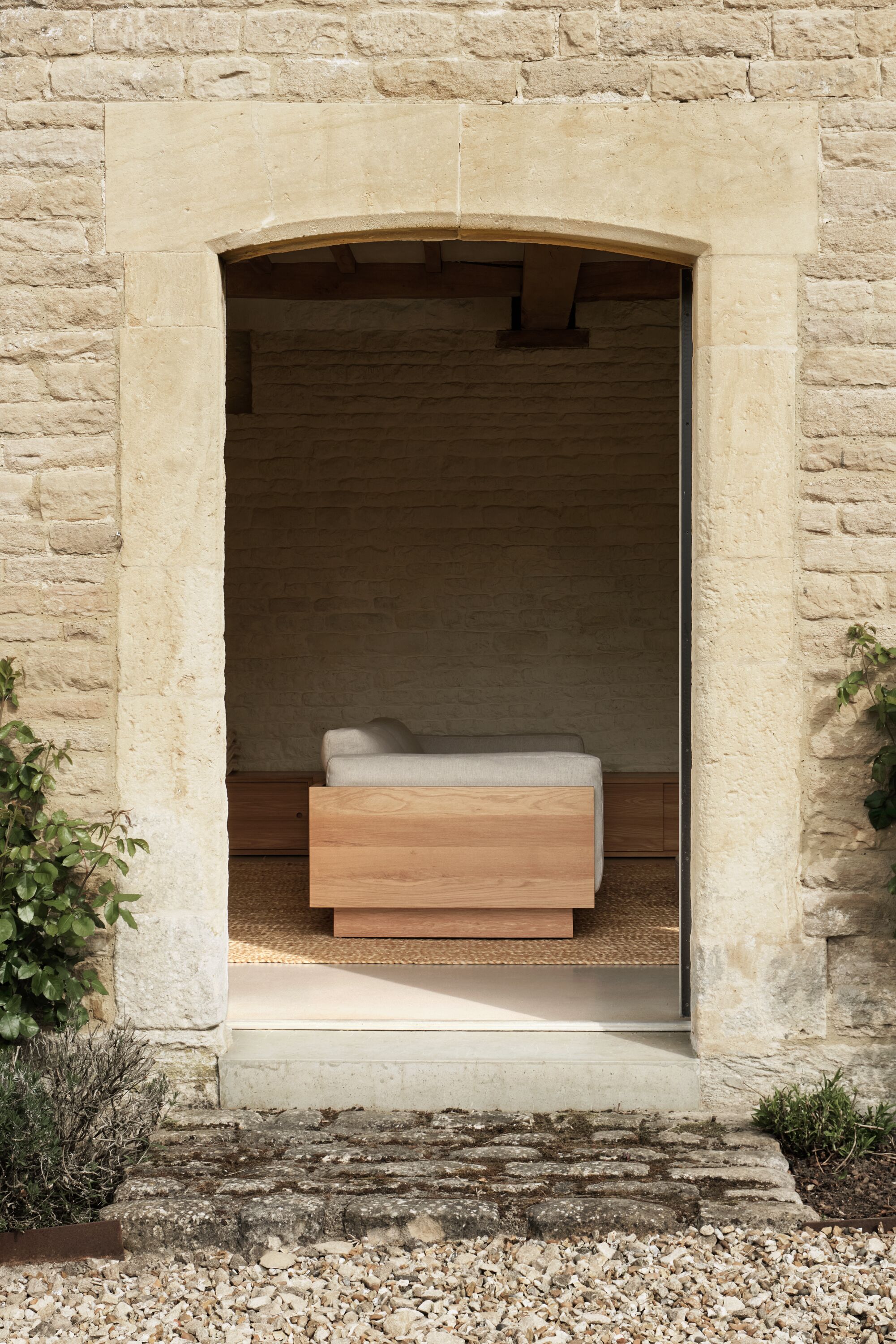 John Pawson sofa for Herman Miller with wooden side and white cushions, shown in an arched doorway