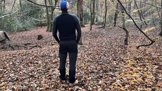 Hiker wearing an Icebreaker 260 ZoneKnit Long Sleeve Half Zip Thermal Top in leafy woods