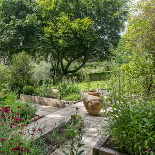 a long paved garden path with raised beds filled with plants and flowers