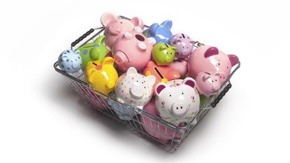 Several different colors and styles of piggy banks are piled into a shopping basket.