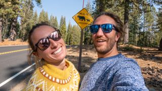 Couple taking selfie on road by 'wildlife crossing' sign