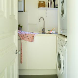 Small cream laundry room with stacked washing machine and tumble dryer