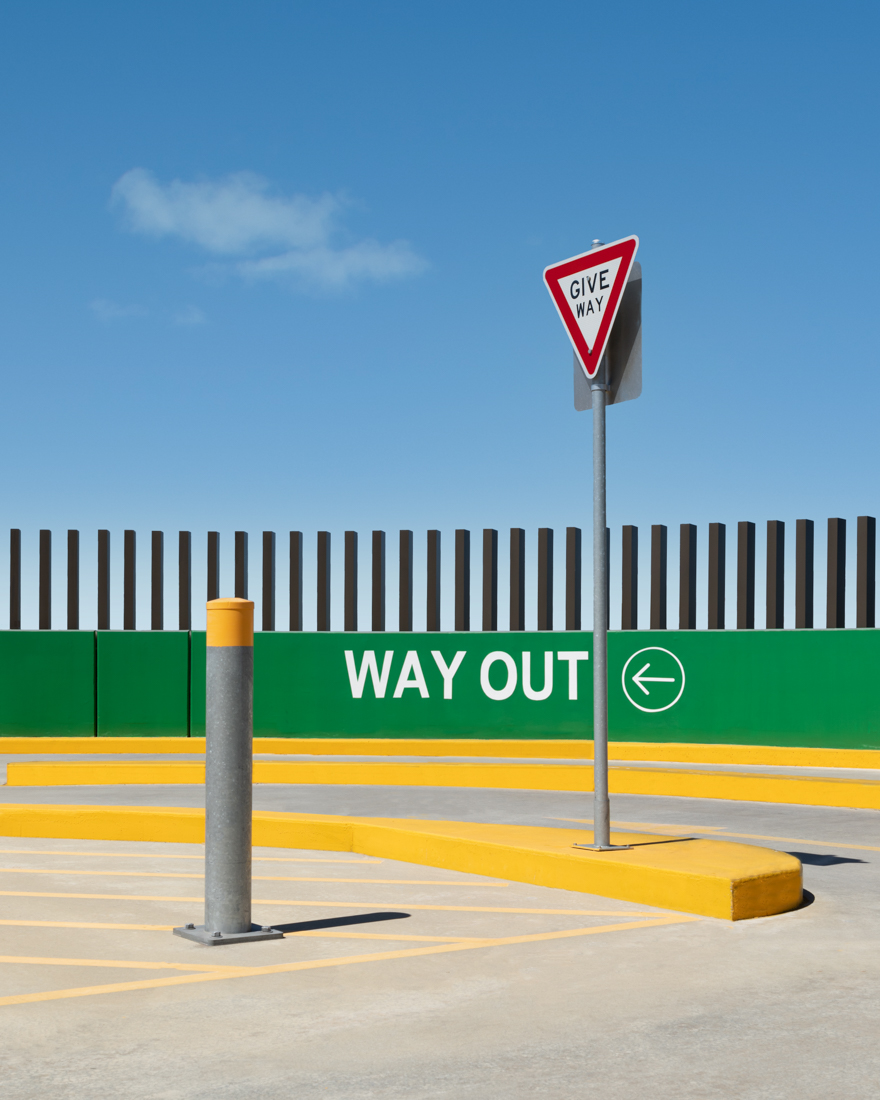 A give way sign in front of way out sign on a wall