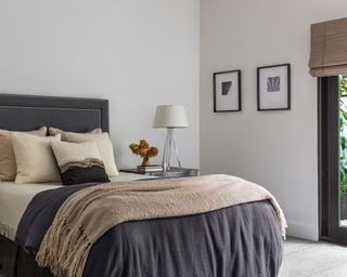 Modern bedroom with gray bed, neutral bedding, artwork on walls.