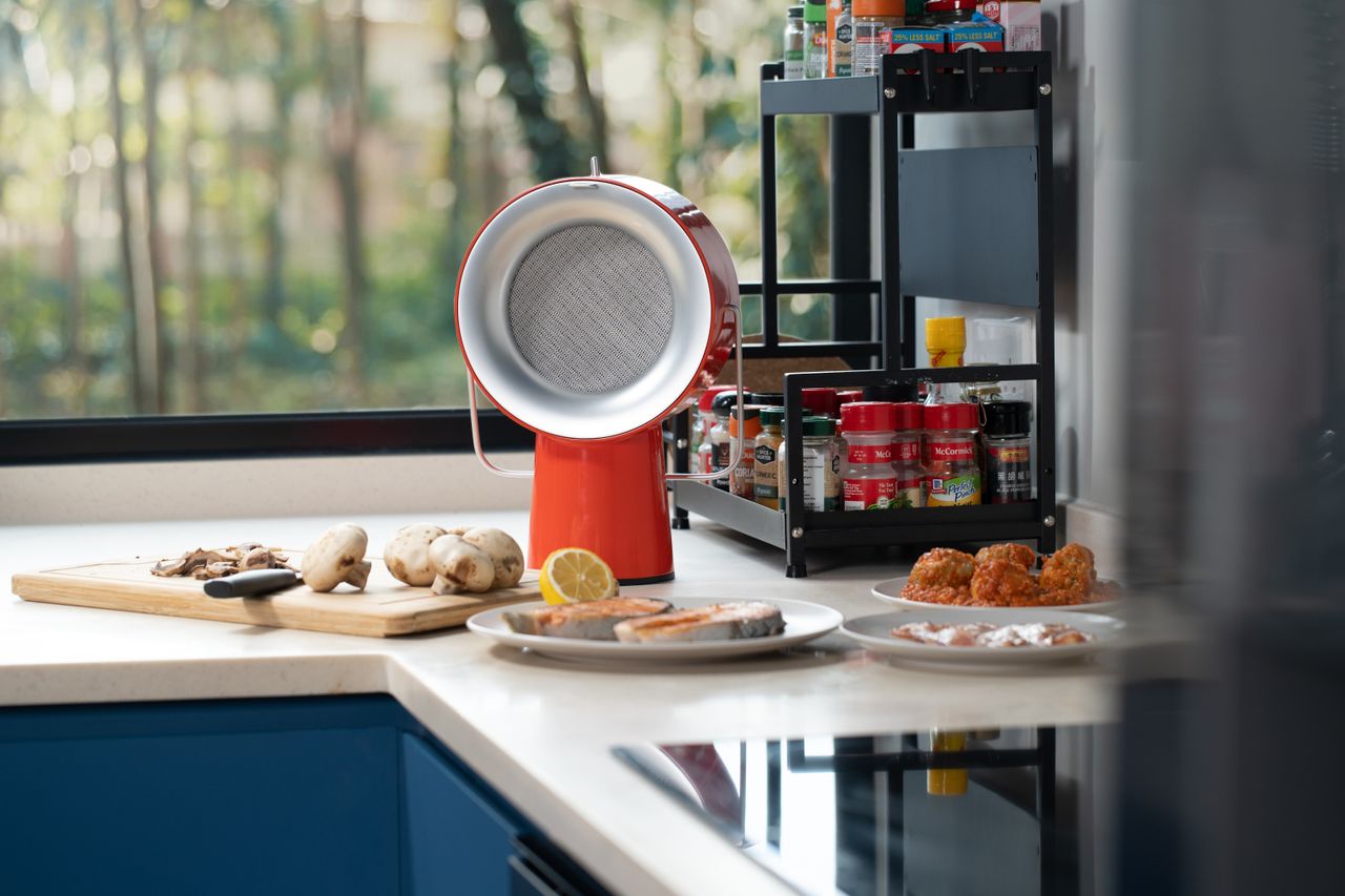 An orange portable range hood sitting by the window on a kitchen top