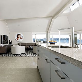 spacious kitchen with limestone worktops leather sofa and monochrome rug