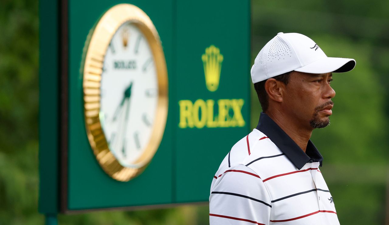 Tiger Woods stands in front of a Rolex advert board