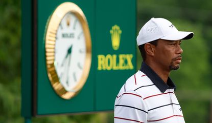 Tiger Woods stands in front of a Rolex advert board