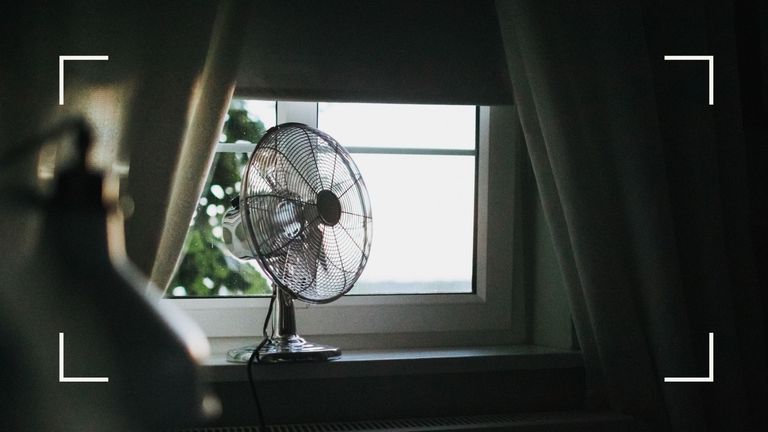 Electric fan sitting just inside an open window