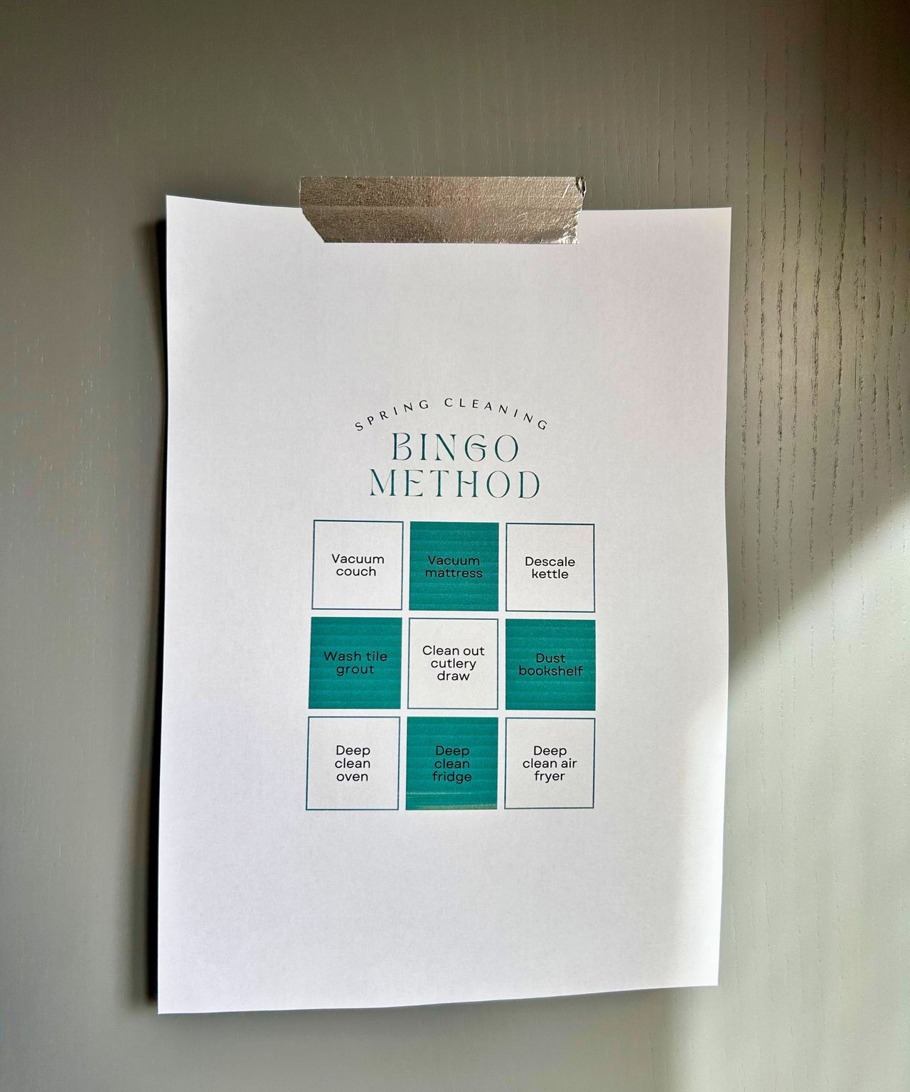 Spring Cleaning Bingo Method on white paper with green boxes and stuck up by silver washi tape