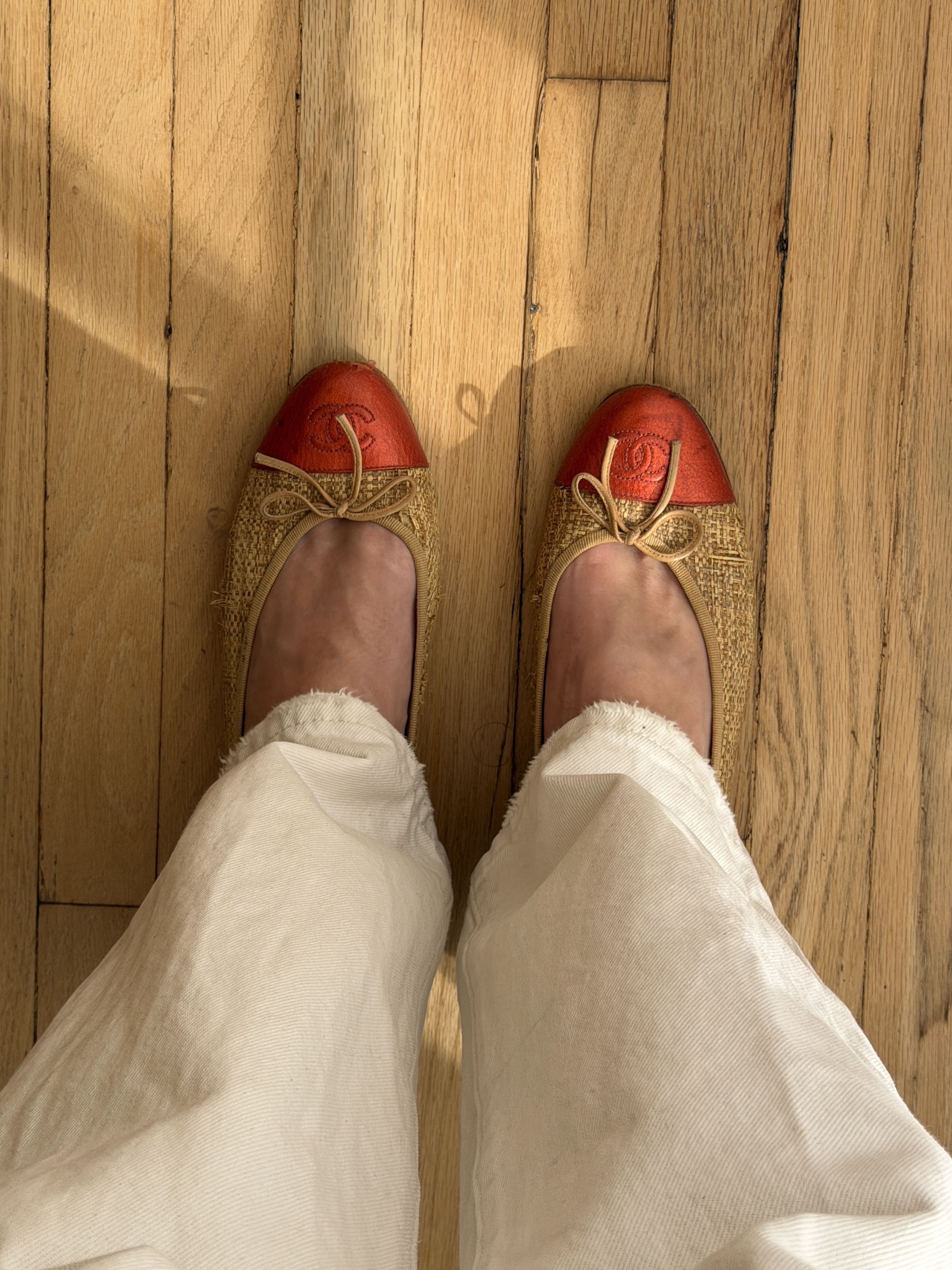 Kathryn Zahorak posing in mirror wearing white jeans, white t-shirt, navy sweater, and red cap ballet flats