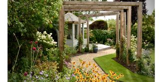 garden with gravel path and pergola with wild flower planting for wildlife