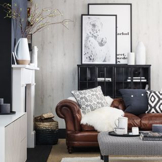 A living room with a brown leather sofa with contrasting scatter cushions next to a fireplace with a storage unit behind it