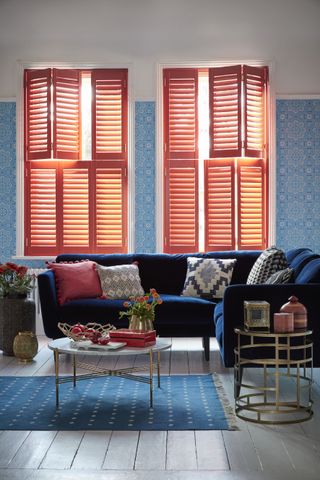 tile inspired wallpaper and coral painted shutters used to mix pattern and prints in a living room by shutterly fabulous