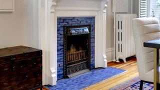 Victorian style fireplace with white surround and small blue tiles hearth and surround