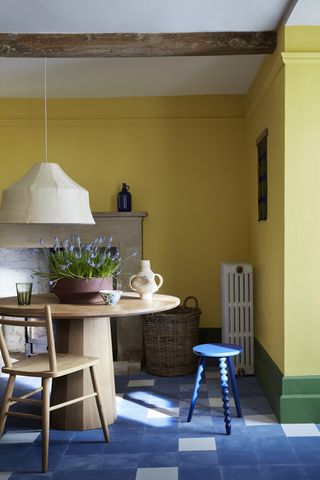 A small dining room with yellow walls and green borders