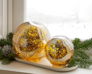 Light-Up Mercury Glass Globe in front of spruce branches and a window overlooking a snowy space