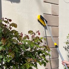 woman scrubbing render on a rendered house