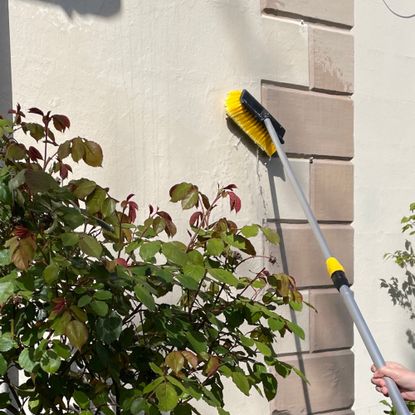 woman scrubbing render on a rendered house