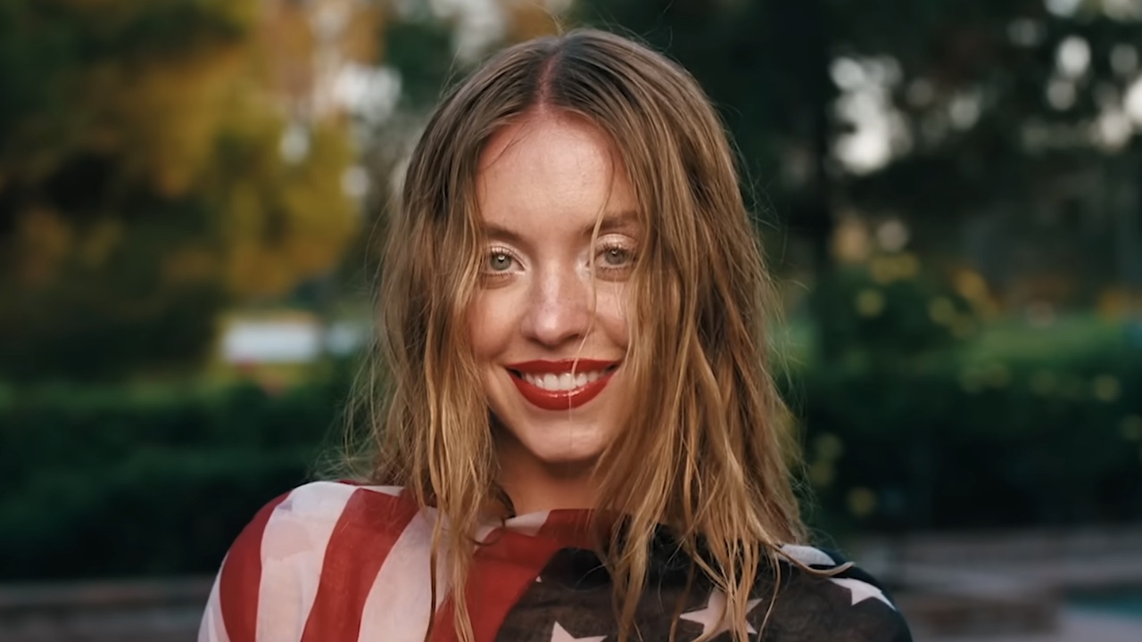 Cassie smiling wrapped in an American Flag in the Euphoria Season 3 trailer.