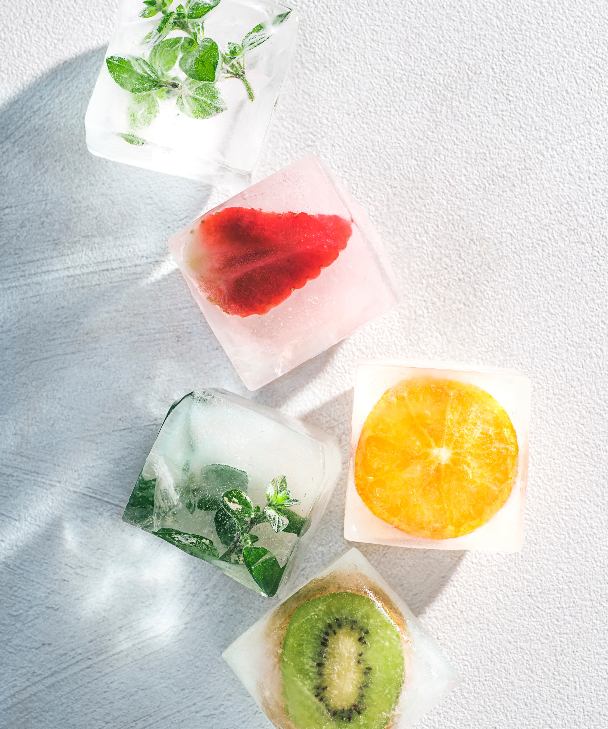 Colorful ice cubes with fruit and herbs