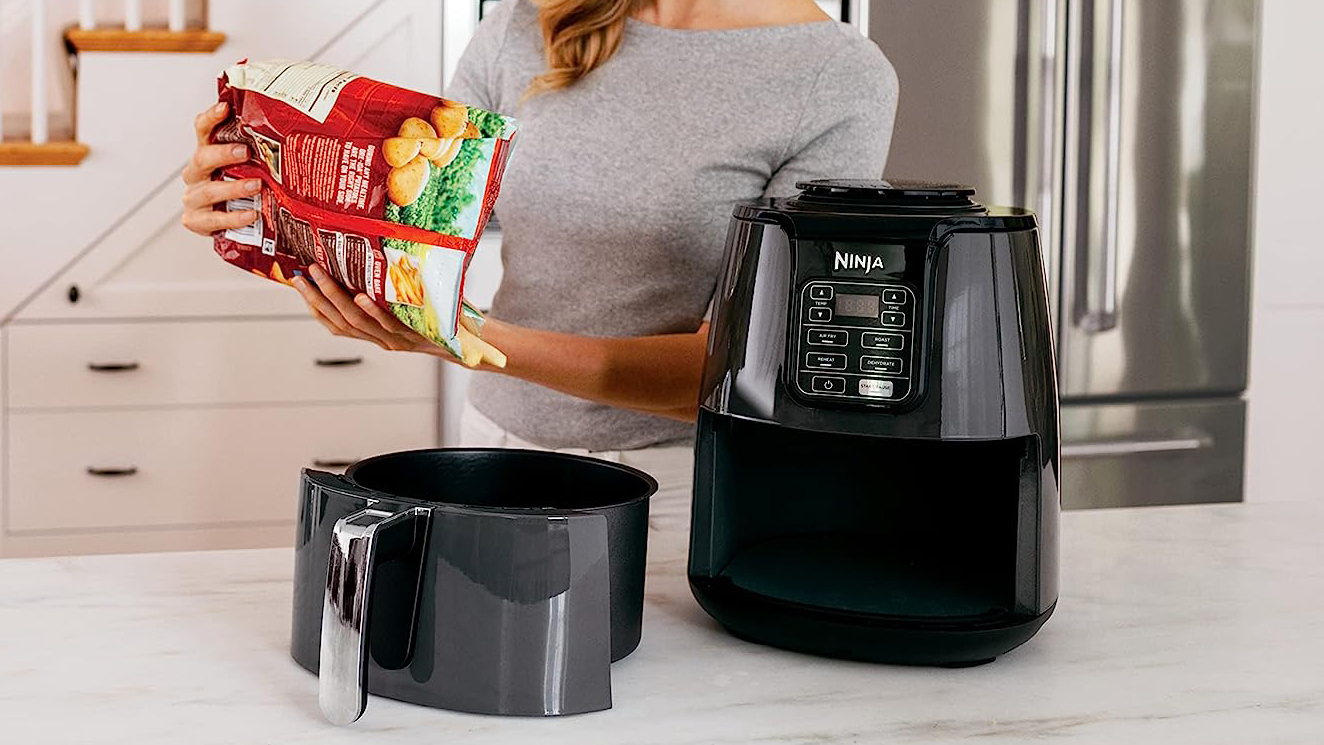 Ninja Air Fryer being used by a woman in a kitchen