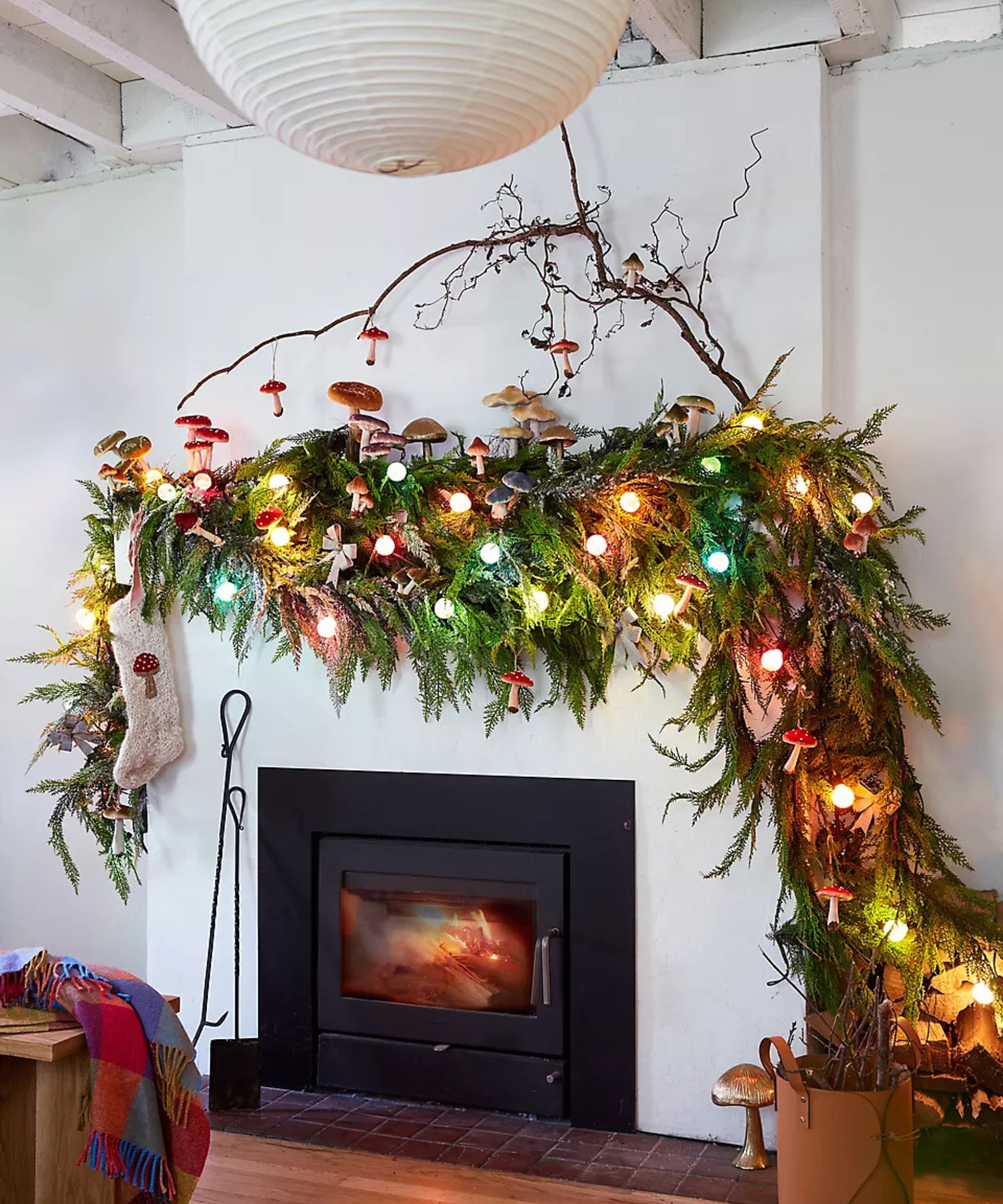 A fireplace decorated with a large evergreen garland filled with colorful lights