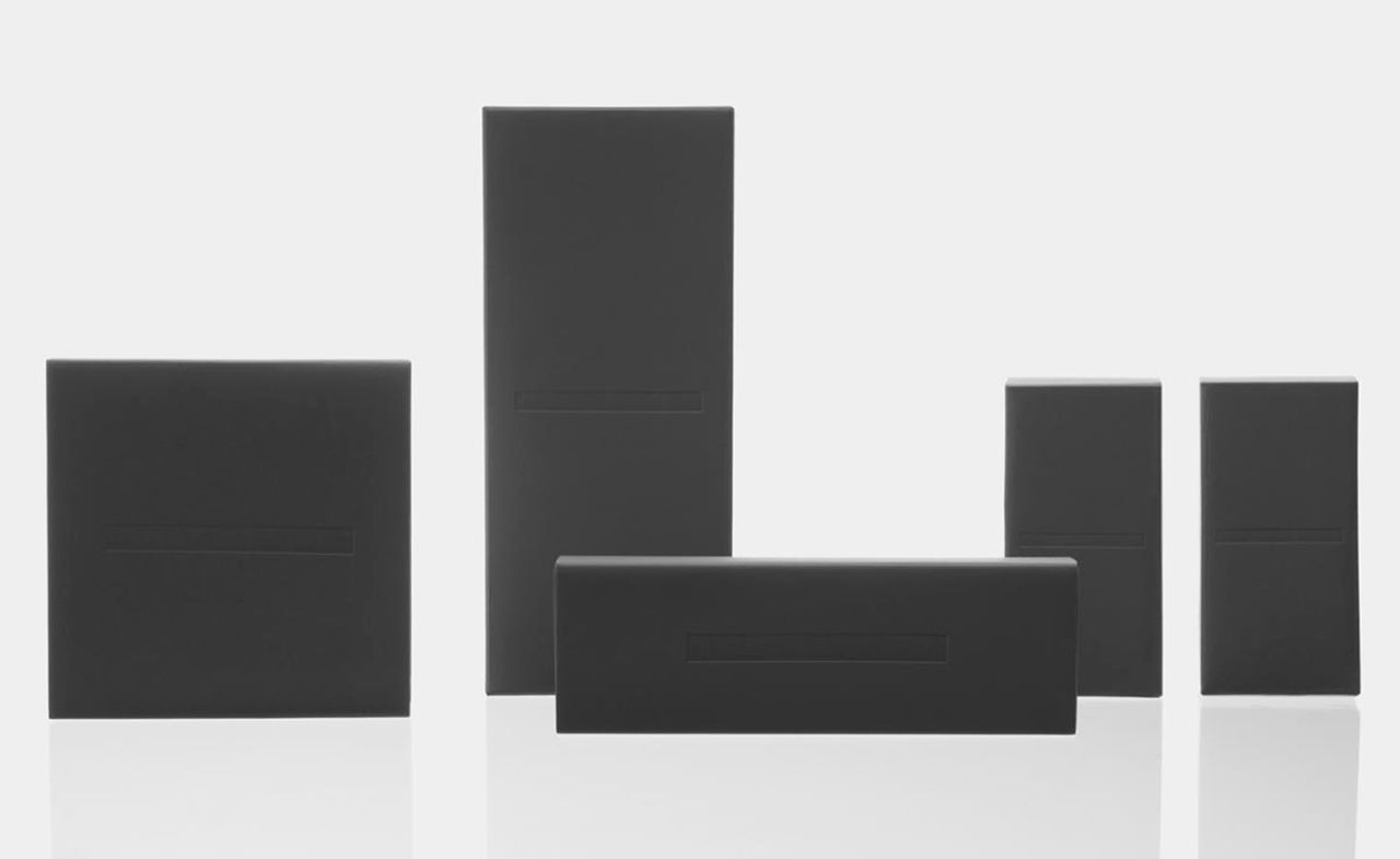 Less skincare packaging of plain black boxes against grey background