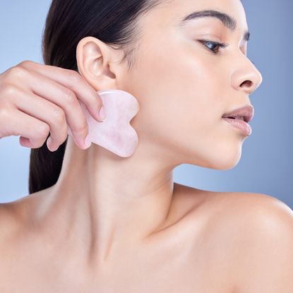 woman using a rose quartz gua sha