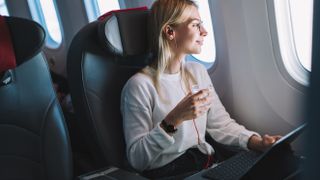 A woman on a Windows laptop in an airplane, looking out the windows