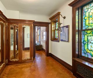 hallway with wood paneling and mirrored closets and stained glass windows