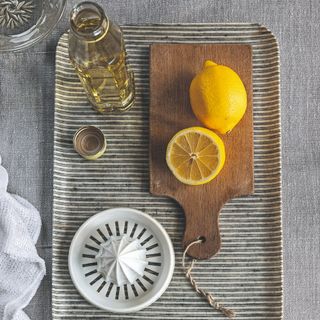 A wooden cutting board with lemons and oil