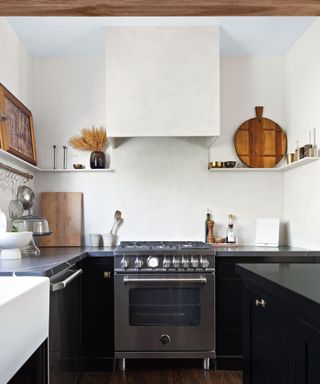 small black gloss kitchen with stainless steel appliances and a plaster cooker hood