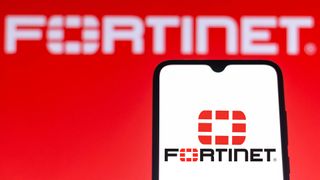 Logo of Fortinet, developer of the FortiGate edge appliance, pictured on a smartphone with logo and branding in background.