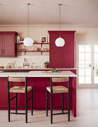 warm red kitchen units with white worktop and seating island