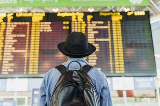 Man with backpack looking at departures board at the airport