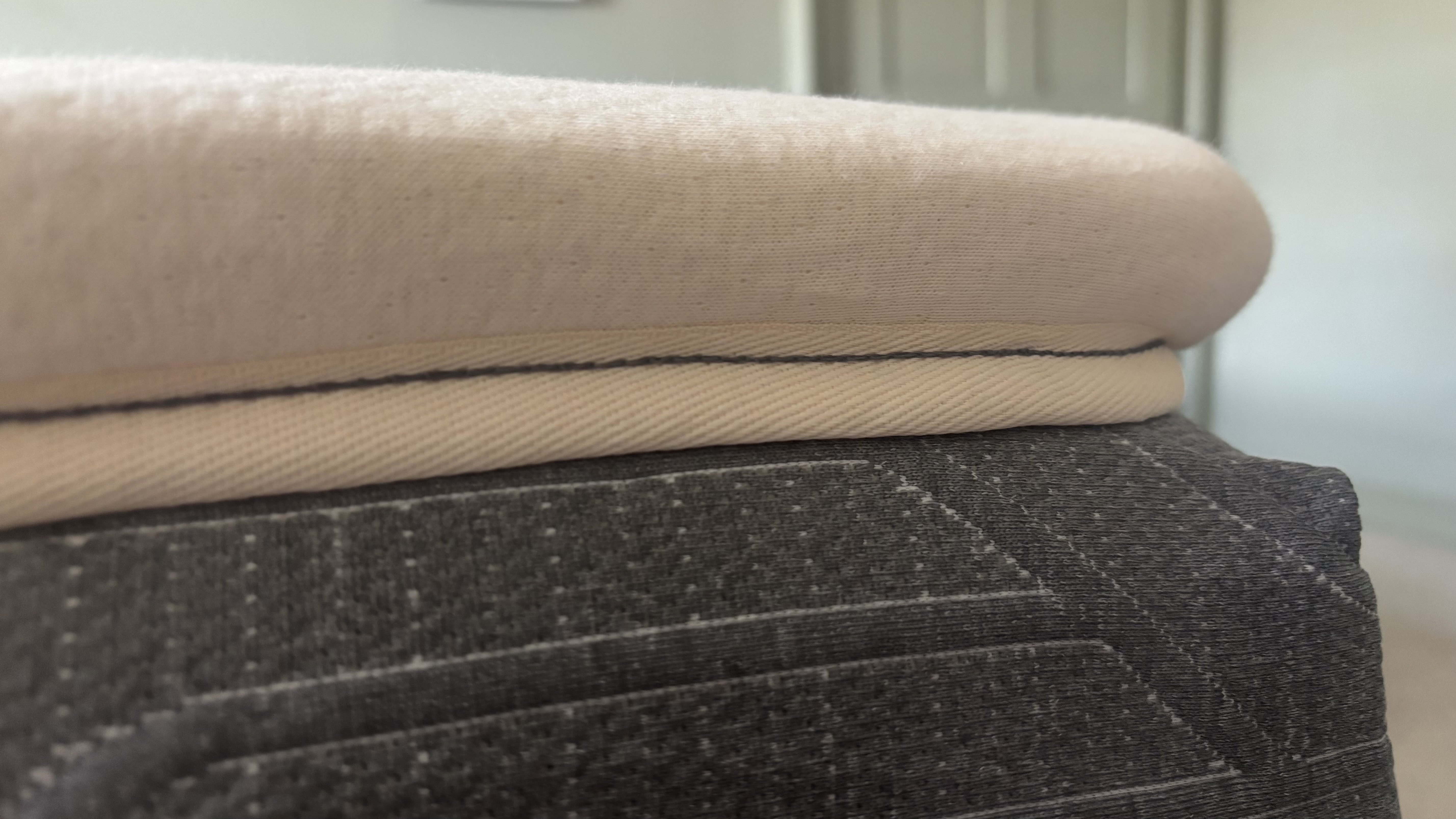 The corner of the Birch Plush Organic Mattress Topper on top of a memory foam bed.