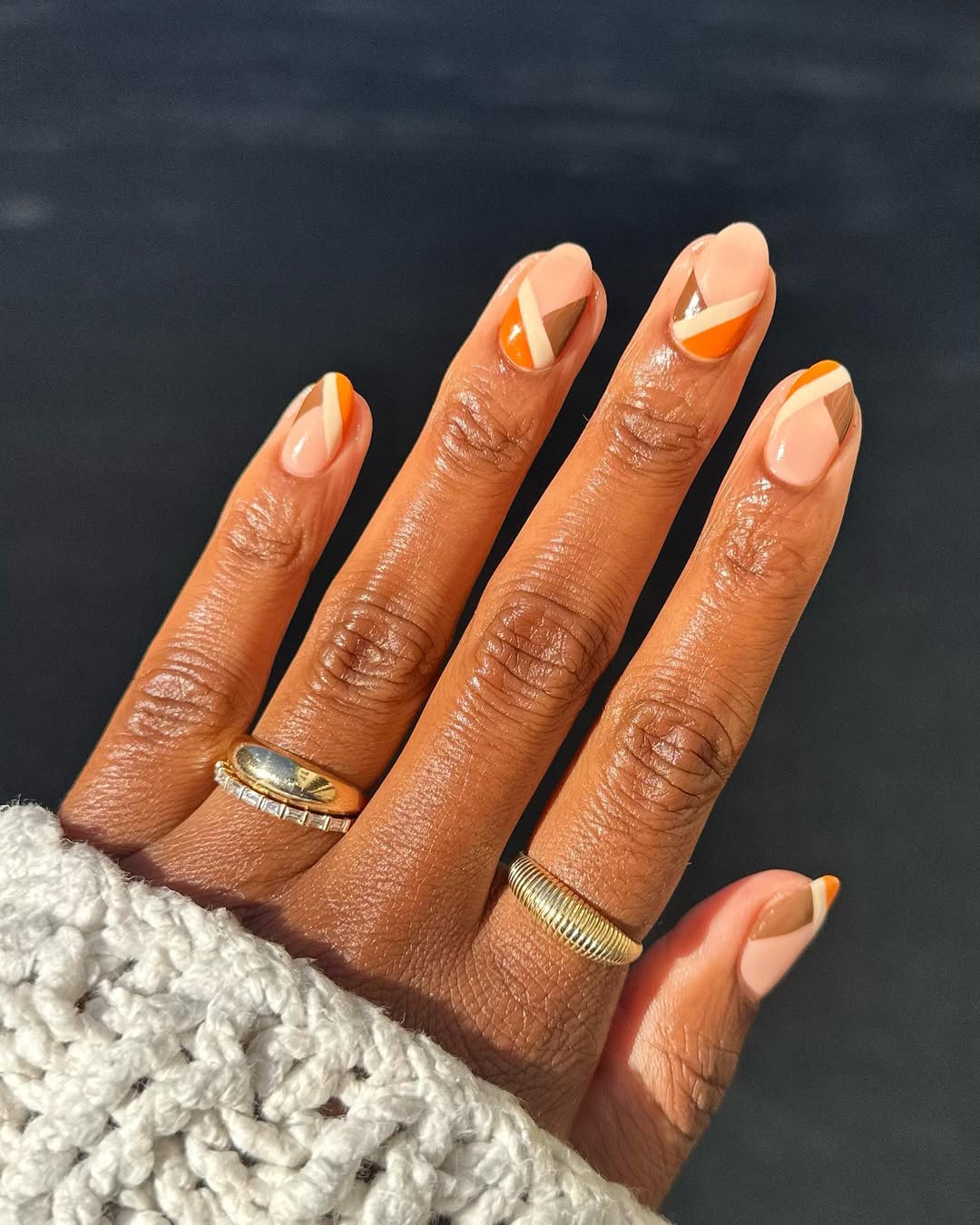 a person wearing a geometric manicure with different shades of brown nail polish