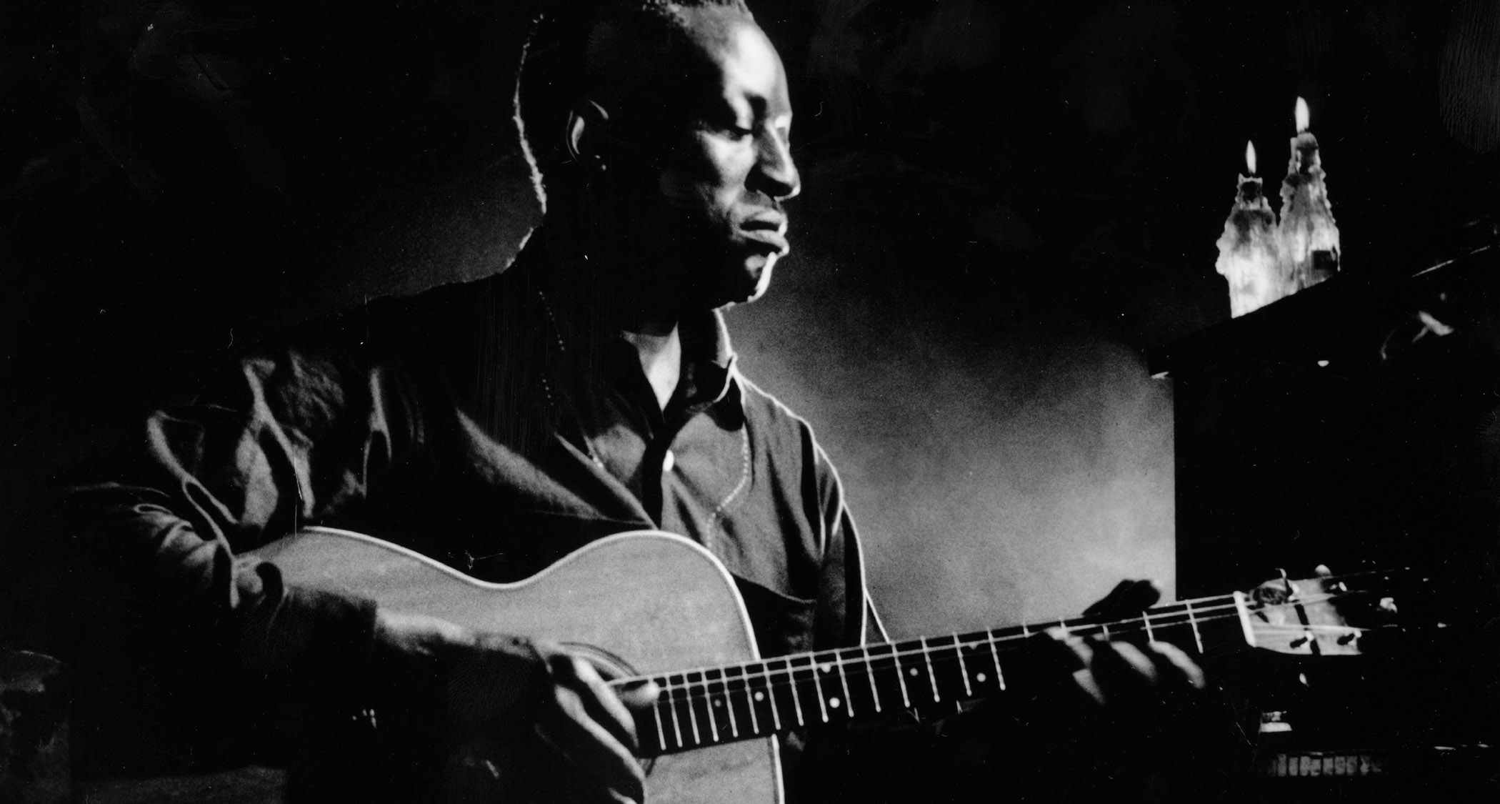 Big Bill Broonzy plays some acoustic blues in this deep contrast B/W archive image.