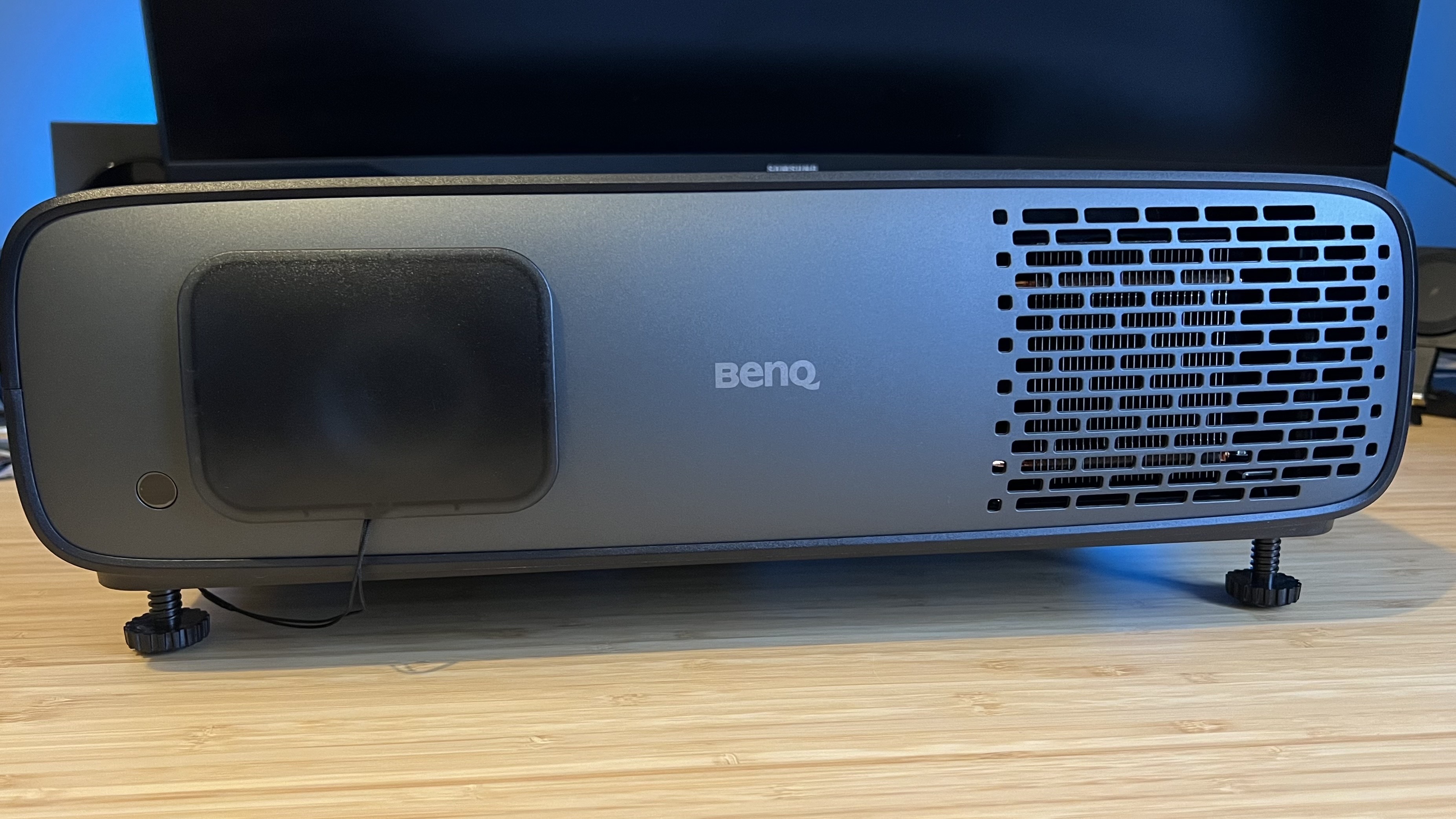 BenQ W4100i projector with lens cap on on a wooden desk
